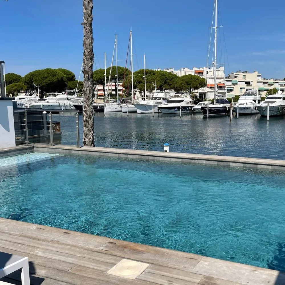 Très belle piscine à débordement près d'un port à l'eau vert grisé
